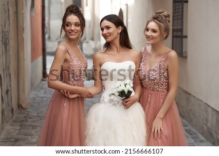 Beautiful bride and bridesmaids in gorgeous elegant stylish silver dress decorated with sequins sparkles. Wedding day in old beautiful European city. Royalty-Free Stock Photo #2156666107