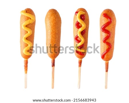 Four corn dogs with different toppings isolated on a white background
