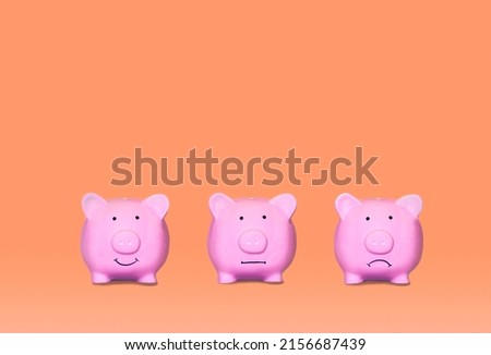 Three little ceramic pigs in different moods with orange background. Mood swing bipolar disorder, depression.  Royalty-Free Stock Photo #2156687439