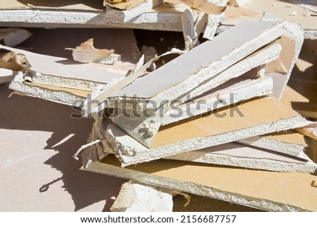 Demolished plasterboard wall, made of plaster and cardboard, with fragments of material and dust in a construction site Royalty-Free Stock Photo #2156687757