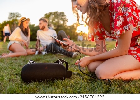 young hipster company of friends having fun together in park smiling listening to music on wireless speaker connecting to smartphone, summer style season Royalty-Free Stock Photo #2156701393