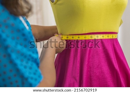 Close up of a Latin fashion designer measuring a dress with a tape