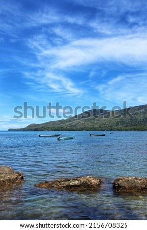 fishing boats anchored on the edge of the island near the beach when the sea is calm and the sky is clear.
