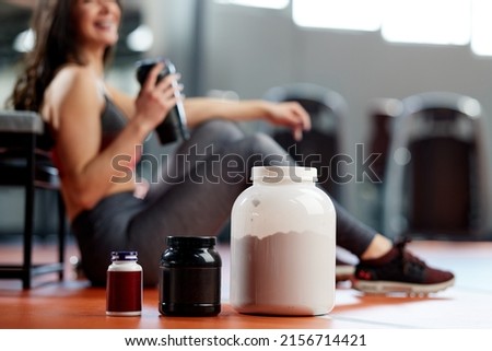 Selective focus on supplements and protein power in gym with a sportswoman. Royalty-Free Stock Photo #2156714421
