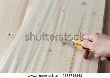 Unpacking a furniture board with a knife. Unpacking a wooden board. Royalty-Free Stock Photo #2156715343