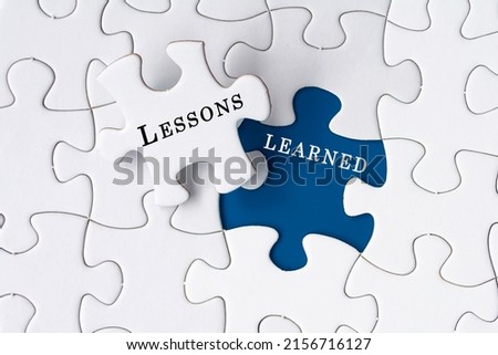 Lessons learned text on Jigsaw Puzzle over dark blue background. Royalty-Free Stock Photo #2156716127