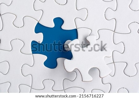 Piece of jigsaw puzzle on blue paper. Flat lay, Directly above. Copy space.