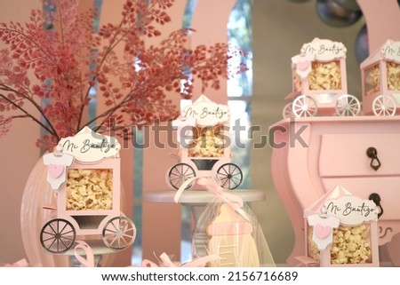 Pink and white popcorn carts with Mi bautizo inscription on a sweet girl table