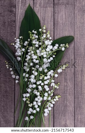 Delicate snow white romantic lilies of the valley on a wooden background with copy space.