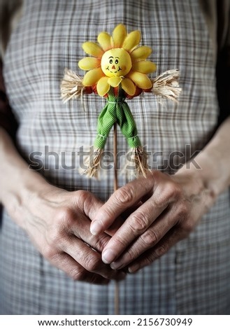 Person in rustic apron holding a scarecrow. Carnival symbol in the woman hands.