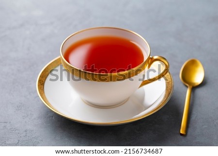 Tea in white cup with gold rim. Grey background. Close up. Royalty-Free Stock Photo #2156734687