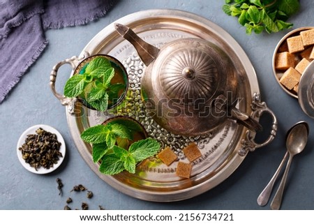 Moroccan mint tea in traditional glasses with vintage teapot on silver tray. Grey background. Close up. Top view. Royalty-Free Stock Photo #2156734721