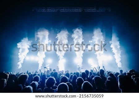 Co2 flame and silhouette of crowd at a music festival in front of bright stage lights Royalty-Free Stock Photo #2156735059