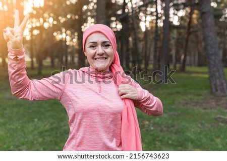 mature woman fighting cancer with a pink scarf on. nature at sunset - breast cancer survivor concept -