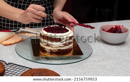 Spreading the cherry filling with spoon in the middle of the cake. Selective focus. Picture for articles about food, confectioners.