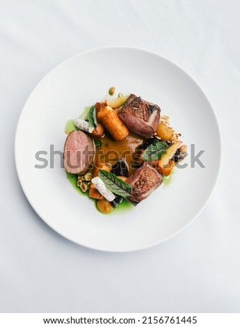 A vertical top shot of a gourmet dish with meat, vegetables, and sauce Royalty-Free Stock Photo #2156761445