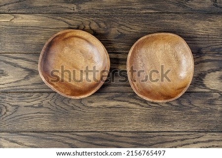 Pair of wooden empty bowls on an oak table, top view