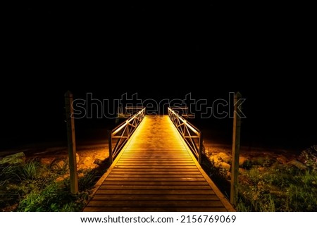 A beautiful shot of a wooden pier illuminated by light at night Royalty-Free Stock Photo #2156769069