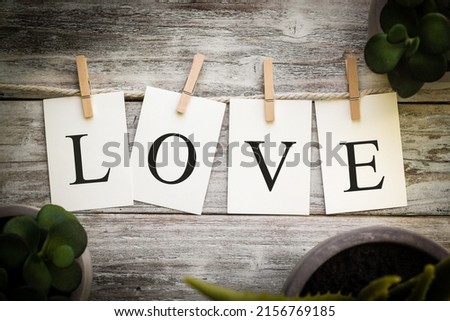 A set of printed cards spelling the word LOVE on an aged wooden background.