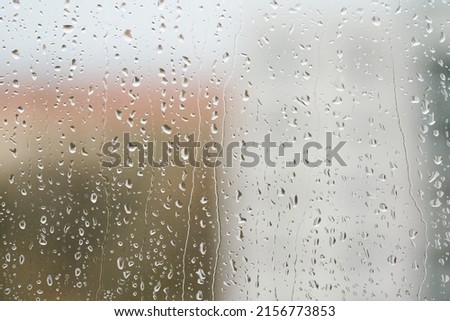 Raindrops on a window pane during rainy weather                               