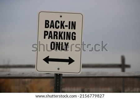 The close up view of a street sign that says "Back In Parking Only" with a double arrow indicating where the sign pertains to.