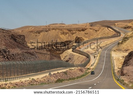 Highway through the Negev Desert on the border with Egypt showing the fence between the countries in Southern Israel
 Royalty-Free Stock Photo #2156786511