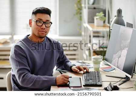 Portrait of male photographer looking at camera while editing pictures at workplace, copy space