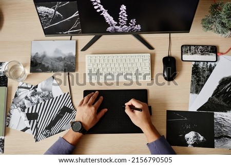 Top view of male photo retoucher using pen tablet while editing pictures, copy space
