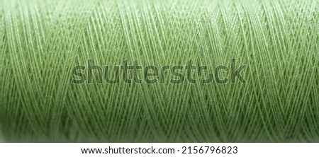 Green sewing thread in spool for sew hobby closeup. Macro bobbin view for needlework Royalty-Free Stock Photo #2156796823