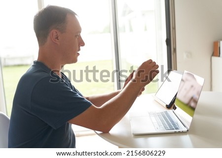 A young man sitting at home in front of a laptop. A serious person working remotely at home. High quality photo