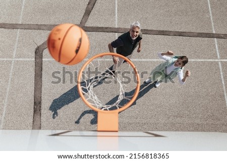 Happy father and teen daughter embracing and standing under a basketball hoop net, directly above
