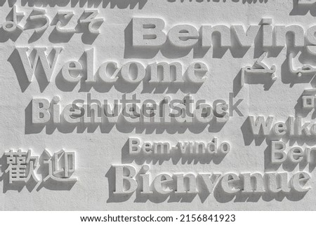 A word welcome written in several languages on a white wall Royalty-Free Stock Photo #2156841923