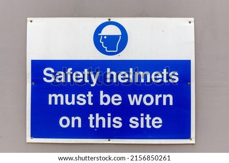 Safety helmets must be worn warning sign with white text on a blue background
