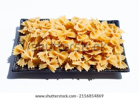 Uncooked bow tie pasta on white background.