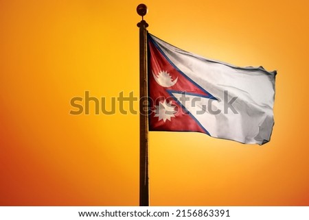 The national flag of Nepal on a flagpole isolated on an orange background
