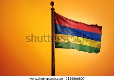 The national flag of Mauritius on a flagpole isolated on an orange background
