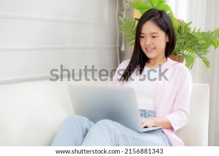 Young asian business woman work from home with laptop computer online to internet on sofa in living room, freelance girl using notebook sitting on couch with comfort and relax, lifestyles concept.
