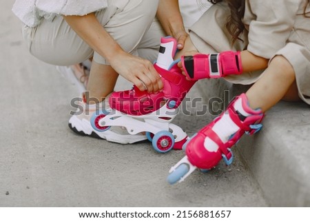 Mother with daughter in a summer park with roller