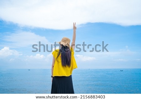 Focus back view happy Asian girl raises her hands up in front of beach at Vung Tau. Travel concept. Concept welcoming, relaxing and enjoying.