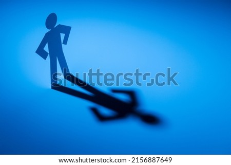 white paper cutout in akimbo figure shape stand on blue light with shadow on white background, in concept of business, free and  individuality.