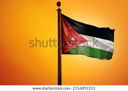 The national flag of Palestine on a flagpole isolated on an orange background