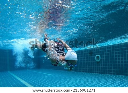 underwater photo of A young woman, she swims and dives in the pool, she does activities, exercises and takes care of her health. with fun swimming