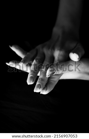 Young, well-groomed women's hands in a black and white photo. Vertical photo.