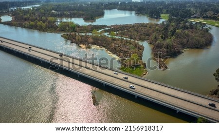 An aerial shot of a long bridge over the river surrounded by forest