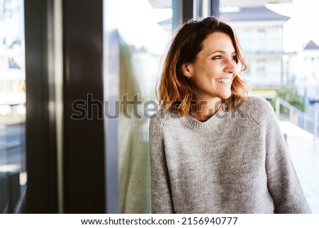 Young woman standing in downtown looking sideways laughing Royalty-Free Stock Photo #2156940777