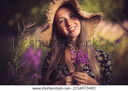 Young woman with summer hat, surrounded purple flowers