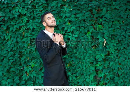 elegant business man standing next to leaves background