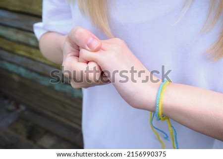 The girl makes gestures with her hands. Squeeze your hand into a fist. Negative defensive concept of communication psychology. Yellow-blue ribbon on the hand of a Ukrainian girl. Ukraine flag colors