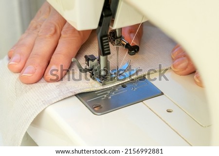 The fabric lies under the needle and foot of the sewing machine.