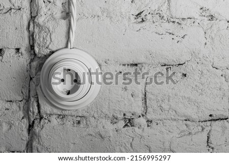 socket with a wire on an old white brick retro wall. loft interior concept